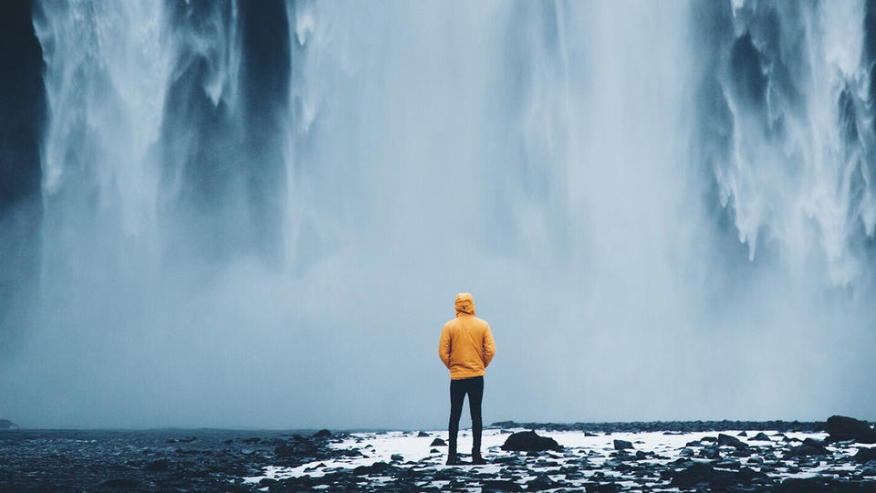 Person standing at the bottom of a waterfall 